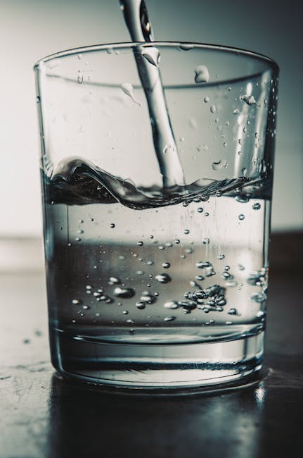 Refreshing water being poured into a glass with visible bubbles.
