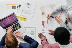 Business meeting with professionals discussing financial reports and graphs at a work desk.