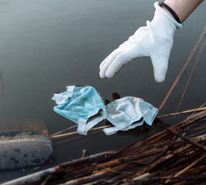 Close-up of a volunteer using gloves to remove waste from a river.