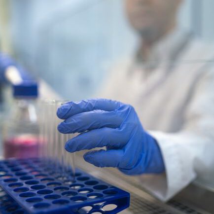 Close-up of a scientist handling test tubes in a laboratory environment.